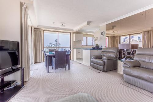 uma sala de estar com um sofá e uma mesa com cadeiras em Ocean Royale em Gold Coast