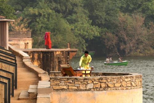 a man sitting at a table on a dock next to the water at RAAS Chhatrasagar, Nimaj, District Pali in Pāli