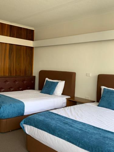 a hotel room with two beds with blue pillows at The Wurruk Motel in Sale