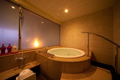 a bathroom with a bath tub in a room at Kikunan Onsen Yubel Hotel in Kumamoto