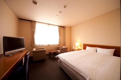 a hotel room with a bed and a television at Kikunan Onsen Yubel Hotel in Kumamoto