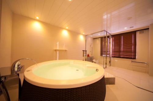 uma casa de banho com uma grande banheira num quarto em Kikunan Onsen Yubel Hotel em Kumamoto