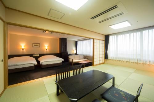 a bedroom with two beds and a table and a dining room at Kikunan Onsen Yubel Hotel in Kumamoto