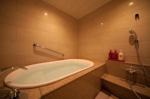 a bathroom with a bath tub and a shower at Kikunan Onsen Yubel Hotel in Kumamoto