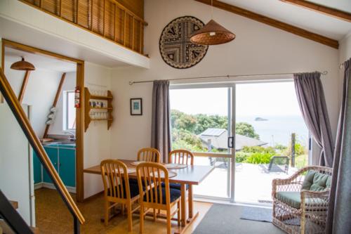 a dining room with a table and chairs and a window at Gull Cottage in Hahei