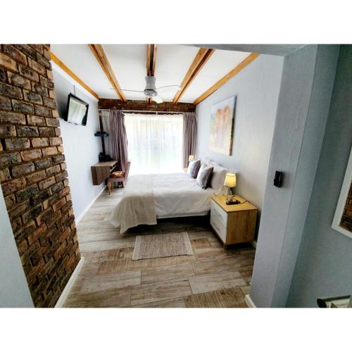 a bedroom with a bed and a brick wall at Waterfall Bed & Breakfast in Midrand