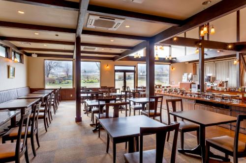 um restaurante com mesas, cadeiras e janelas em Hotel Hakuba em Hakuba