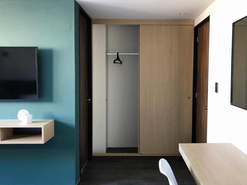 a room with a door with a television and a table at Hotel Conde Alameda CDMX in Mexico City