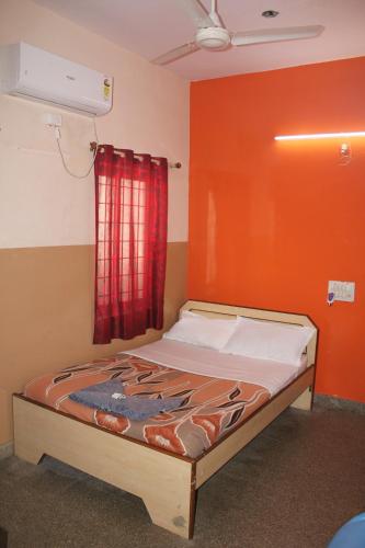 Cama en habitación con pared roja en Santosh Lodge, en Dod Ballāpur