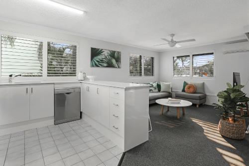 uma cozinha com armários brancos e uma sala de estar em Riverside location, Noosa Sound em Noosa Heads