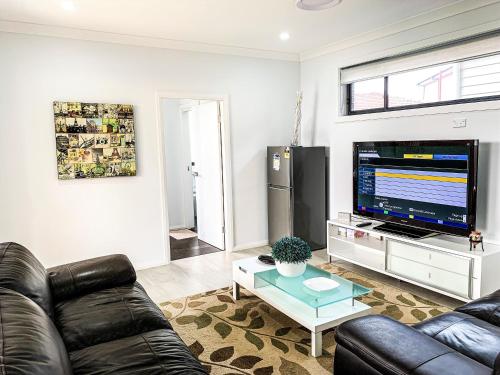 a living room with a couch and a flat screen tv at Revesby New Self Contained Granny Flat in Revesby