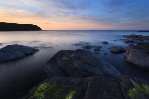 a beach with rocks in the water at sunset at Mill Of Nethermill Holidays in Pennan