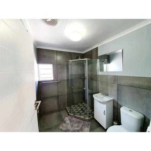 a bathroom with a shower with a toilet and a sink at Waterfall Bed & Breakfast in Midrand