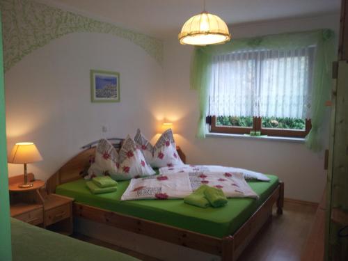 a bedroom with a bed with green sheets and pillows at Ferienwohnung Anna Zechner in Flattach