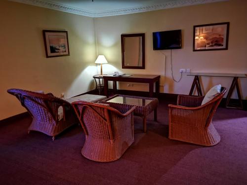 Habitación de hotel con sillas, mesa y TV en The Grand Beach Resort Port Dickson, en Port Dickson
