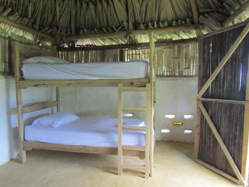 a bunk bed in a straw roofed room at Reserva Atashi in La Poza