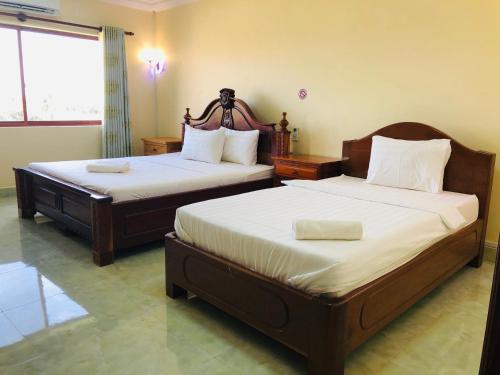 two beds in a hotel room with two beds sidx sidx sidx at Savet Guesthouse in Stœ̆ng Trêng