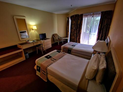 a hotel room with two beds and a desk at The Grand Beach Resort Port Dickson in Port Dickson