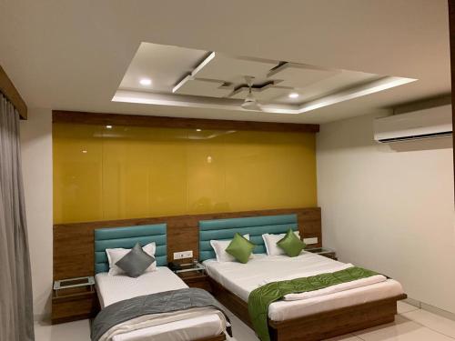 a bedroom with two beds and a ceiling at HOTEL SATKAR CHHATRAL in Kalol