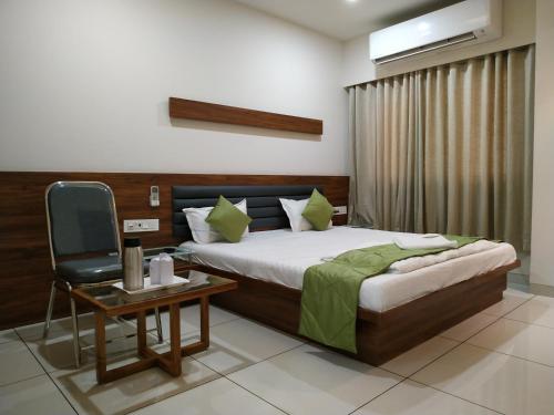 a bedroom with a bed and a chair and a table at HOTEL SATKAR CHHATRAL in Kalol