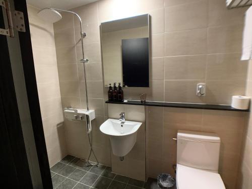 een badkamer met een wastafel, een toilet en een spiegel bij Jeju Renaissance Hotel in Jeju-stad