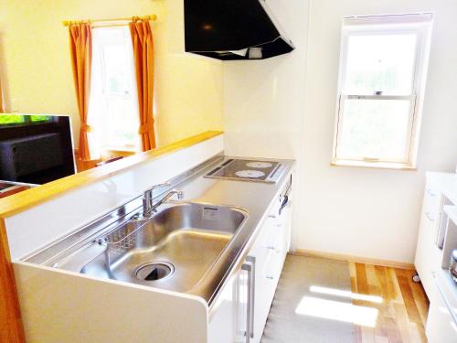 a kitchen with a stainless steel sink and a stove at Hotel Resort Inn Niseko in Niseko