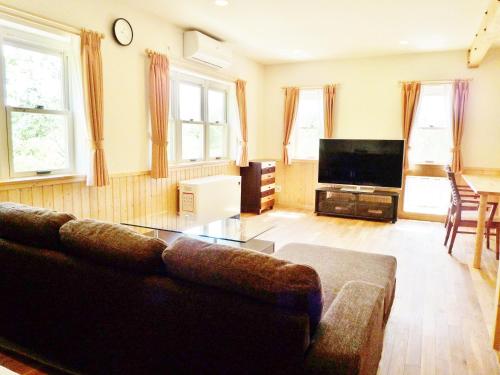 a living room with a couch and a flat screen tv at Hotel Resort Inn Niseko in Niseko