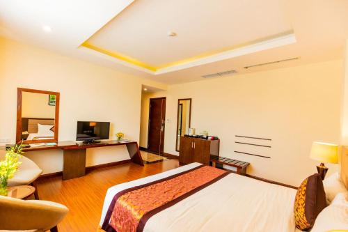 a bedroom with a bed and a desk with a television at Muong Thanh Holiday Quang Binh Hotel in Dong Hoi