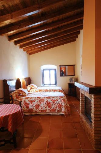 a bedroom with two beds and a fireplace at Palacio Viejo de Las Corchuelas in Torrejón el Rubio