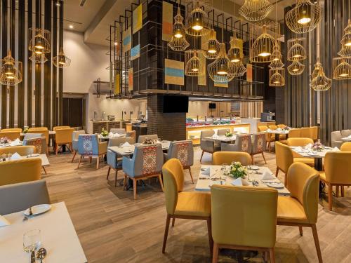 a restaurant with tables and chairs and chandeliers at Grand Mercure Ahmedabad GIFT City - An Accor Hotels Brand in Gandhinagar