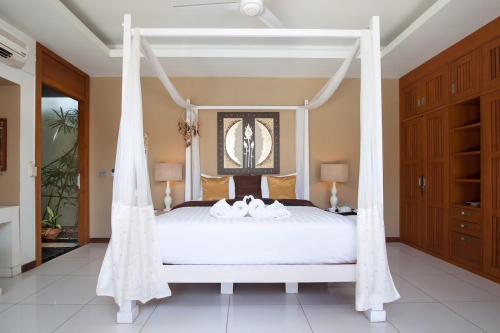 1 dormitorio con cama con dosel y 2 toallas blancas. en Samui Blu, villa with private pool, en Choeng Mon Beach