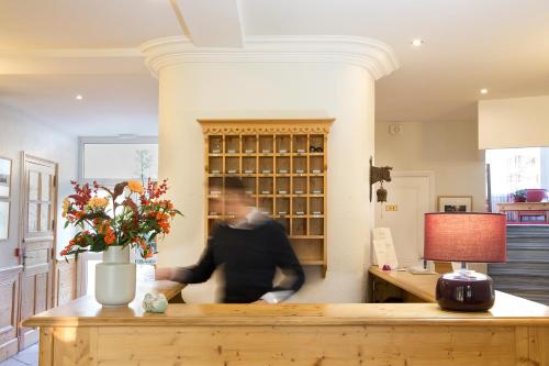a man is standing at a counter in a room at Hotel Les Mésanges in Saint-Martin-dʼUriage