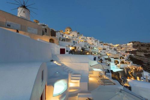 a view of a town at night with a windmill at The Architect's Cave House in Oia