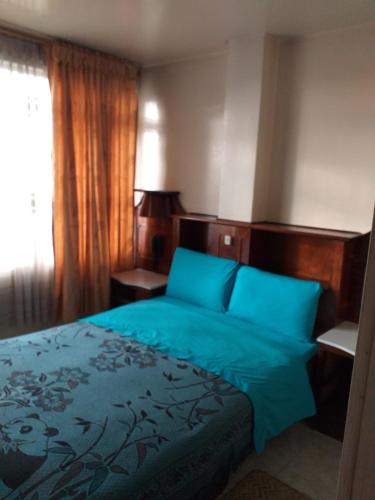 a bedroom with a bed with blue sheets and a window at Hotel Plata in Bogot&aacute;