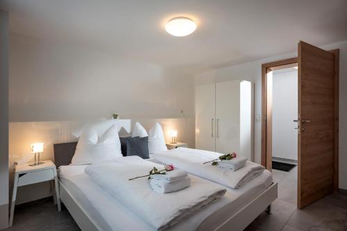 ein Schlafzimmer mit 2 Betten mit weißer Bettwäsche und Blumen darauf in der Unterkunft Am Brummelbach by NV-Appartements in Westendorf