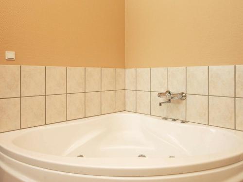 a white tub in a bathroom with orange walls at 8 person holiday home in Hj rring in Hjørring