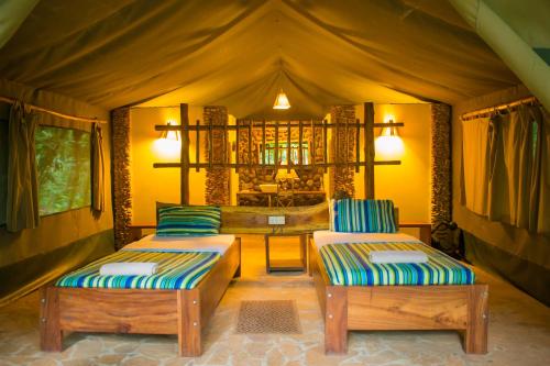a room with two beds and a table in a tent at Kibale Forest Camp by NATURE LODGES LTD in Kyenjojo