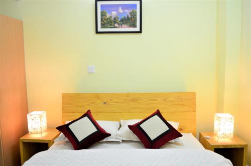 a bedroom with a bed with two lamps and a picture on the wall at Tanani Newa Home Arnnapurna in Pātan