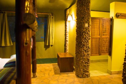 a room with a stone pillar and a room with a bed at Kibale Forest Camp by NATURE LODGES LTD in Kyenjojo