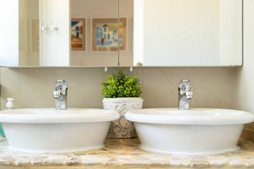 two sinks in a bathroom with two faucets at Comfy Central with Balcony and Views in Cape Town
