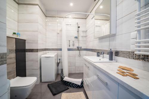 a white bathroom with a toilet and a sink at Mazurskie Klimaty in Olsztyn