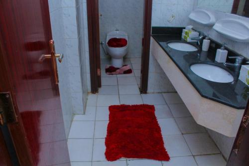 a bathroom with a toilet and two sinks and a red rug at Dar Al Bayan Hotel in Mecca