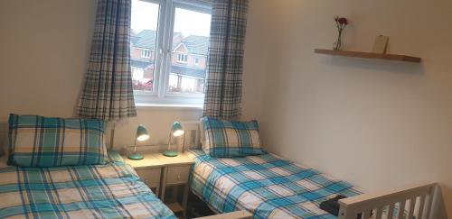1 dormitorio con 2 camas individuales y ventana en Hollybrae house Sleeps up to 6, en Kirkcaldy