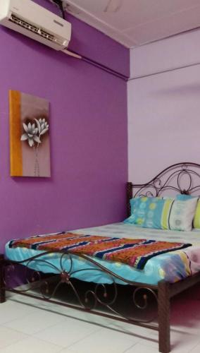 a bedroom with a purple wall with a bed at Bajet Homestay - low cost houses in Kuantan