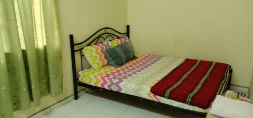 a small bed with colorful sheets and pillows in a bedroom at Bajet Homestay - low cost houses in Kuantan