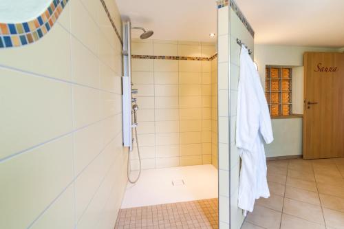 uma casa de banho com chuveiro e um roupão na porta em Gänschen klein em Ellscheid
