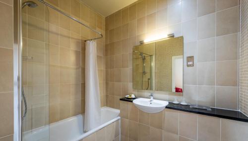 a bathroom with a sink and a tub and a mirror at The Pennington Hotel in Ravenglass