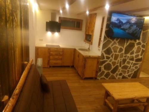 a kitchen with wooden cabinets and a tv on the wall at László apartman in Harghita-Băi