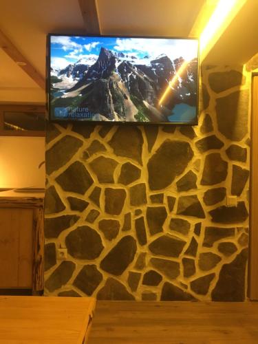 a flat screen tv on a stone wall at László apartman in Harghita-Băi