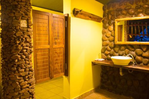 a bathroom with a sink and a stone wall at Kibale Forest Camp by NATURE LODGES LTD in Kyenjojo